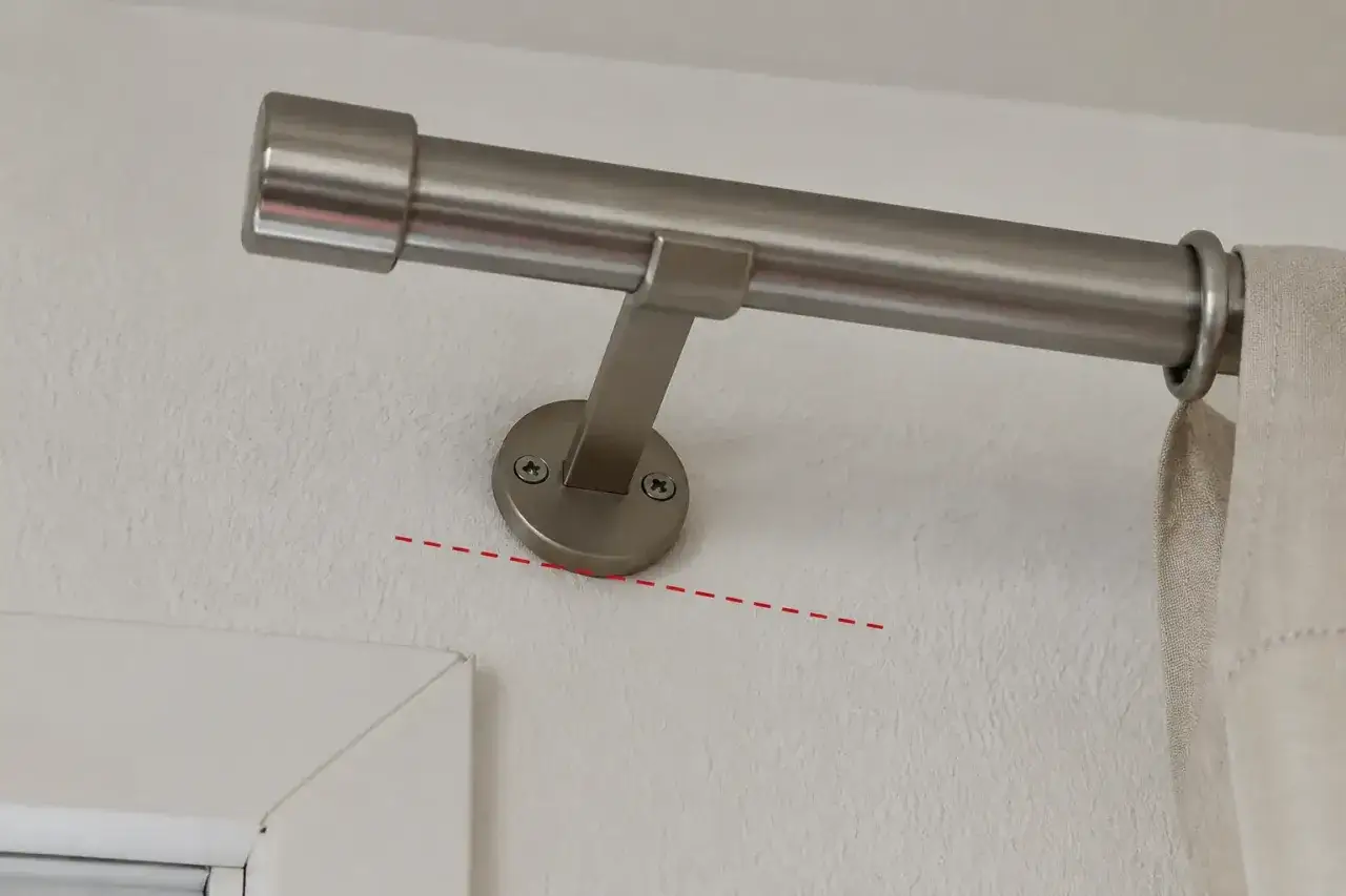 Ein Vorhang wird an der Wand befestigt. Die Halterung der Gardinenstange ist mit Schrauben an der Wand montiert.